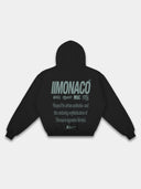 Black streetwear hoodie mockup with green Monaco back print, layered typography and ribbed trim.