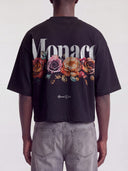 Black Bloom boxy tee on model, back view with white Monaco wordmark over faded roses.
