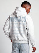 Back view of Monaco tapered hoodie on model in heather gray with light blue logo stack and oversized lifestyle print.