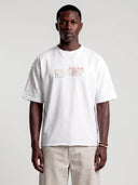 Model wearing the arctic white Monaco Champ oversized tee, front view with cream lettering and colorful accents.