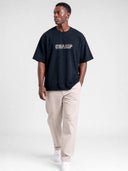 Model wearing the navy blue Monaco Champ raw hem tee, front view with cream block logo and red script.