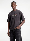 Dark grey Monaco Champ heavyweight tee worn by model, close front view highlighting the layered chest logo.