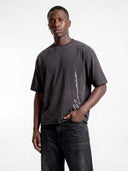 Dark grey Untamed heavyweight tee worn by model, front view highlighting the vertical signature print.
