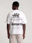 Model in arctic white Open Land raw hem T-shirt, back view showing the oversized three-horse and Monaco graphic.