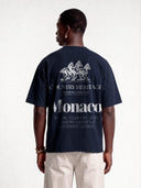 Navy blue Open Land heavyweight tee worn by model, back view with white horses and large Monaco graphic.
