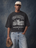 Monaco Social Club Baseball Club: model in a washed black cropped boxy tee with a vintage city skyline and ballpark baseball front graphic, holding a leather glove