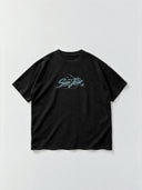 Monaco Social Club San Jose Blur Tee in faded black, front flat lay showing teal Hockey Club artwork and an oversized boxy cut.