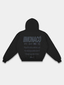 Black Monaco Aesthetic tapered hoodie mockup, back view with tonal dark logo stack and statement print.