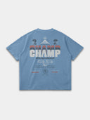 The Champ Tee in slate blue, back mockup with cream, red and blue typography and Monaco crest graphics.