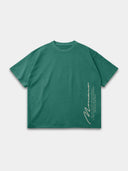 The Untamed Tee in vintage green, front mockup with vertical Monaco signature and motto print near the hem.