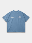 Slate blue Open Land oversized T-shirt, front mockup showing white Monaco and three-horse chest graphics.
