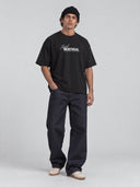 Front view of a model wearing the black Monaco Social Club Montreal Blur Tee with white chest lettering, dropped shoulders and a raw bottom hem.