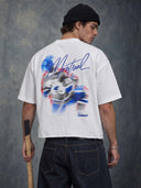 Model holding a hockey stick, wearing the white Monaco Social Club Montreal Blur Tee with red and blue back artwork and blue Montreal script.