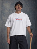 Front view of the white Monaco Social Club Montreal Blur Tee on a model, showing red and blue Hockey Club lettering and a boxy fit with a raw bottom hem.