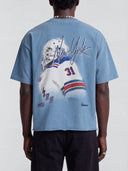 Back view of a model wearing the slate blue Monaco Social Club New-York Blur Tee with goalie artwork and a rolled raw hem.