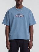 Front view of a model wearing the slate blue Monaco Social Club New-York Blur Tee, showing the Hockey Club graphic and oversized boxy fit.
