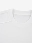 White Monaco paneled shirt close-up showing ribbed crew neck and structured shoulder seam.