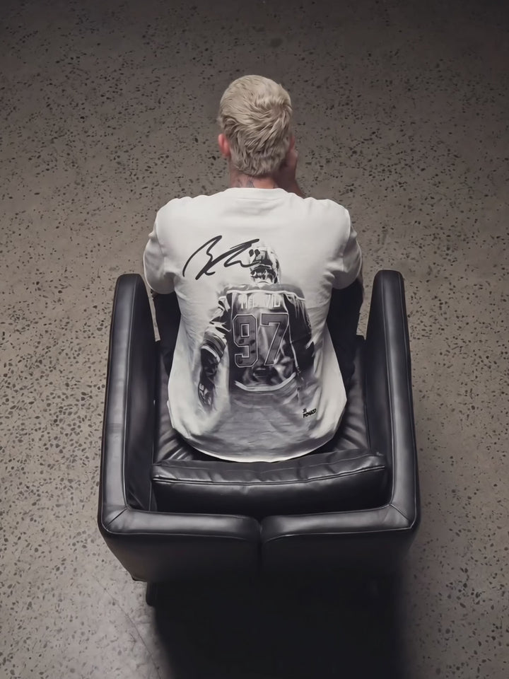 Seated model wearing multiple Raw Hem T-shirts from different collections between takes.