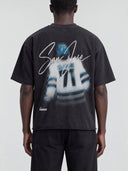 Back view of a model wearing the faded black Monaco Social Club San Jose Blur Tee with number 71 artwork and a rolled raw hem.