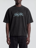 Front view of a model wearing the faded black Monaco Social Club San Jose Blur Tee with teal chest artwork and dropped shoulders.